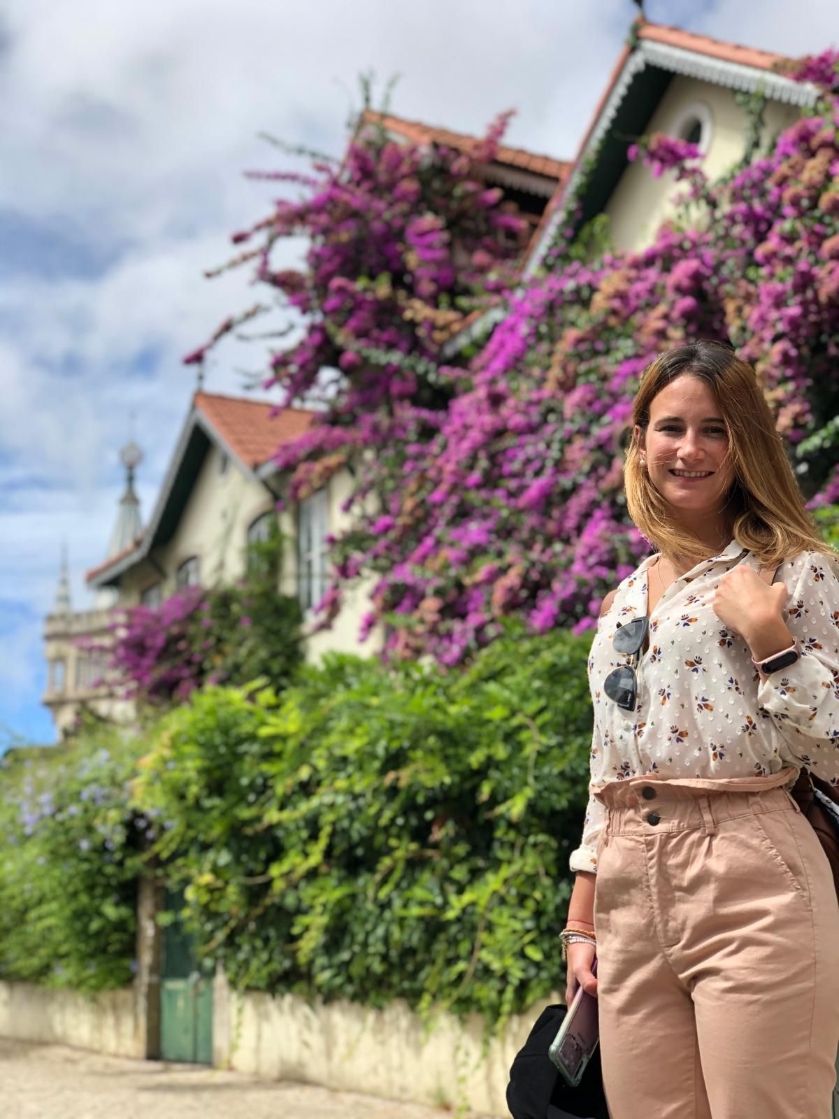 Silvia smiling in front of a house covered in bougainvillea.